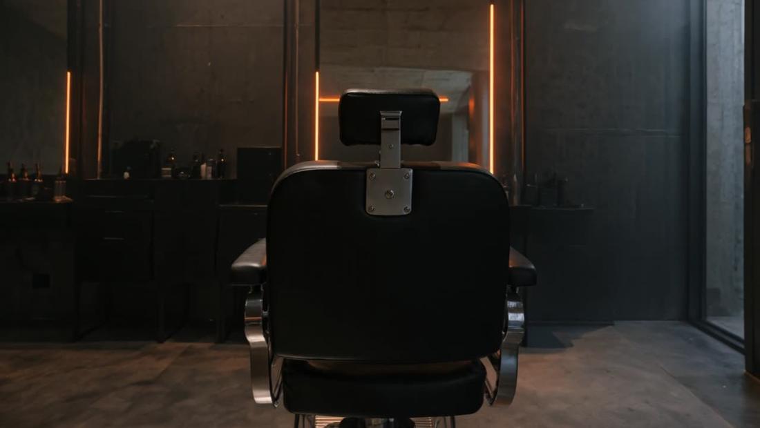 A black barber chair under orange light